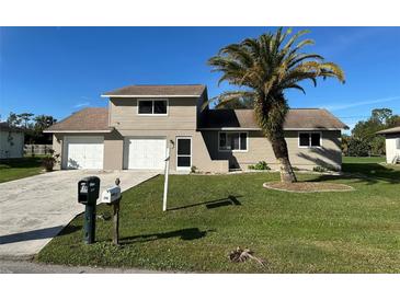 Tan two-story house with a two-car garage and palm tree at 240 Cicero Nw St, Port Charlotte, FL 33948
