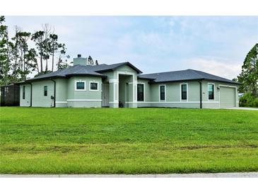 Single-story home with light green exterior, landscaping, and a two-car garage at 5148 Guava Ter, Port Charlotte, FL 33981