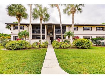 Two-story condo building with lush landscaping and walkway at 1515 Forrest Nelson Blvd # H108, Port Charlotte, FL 33952