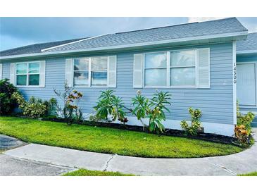 Quaint light-blue house with a well-maintained lawn and sidewalk at 14300 Worthwhile Rd, Port Charlotte, FL 33953