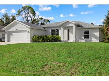 Newly built home with a two car garage and lush lawn at 8450 Malcolm Ave, North Port, FL 34287