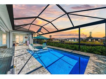 Screened-in pool area with two lounge chairs and an umbrella, overlooking a scenic canal view at 630 Coronado Dr, Punta Gorda, FL 33950