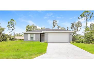 Newly built single-story home with gray exterior, white garage door, and green lawn at 481 Guild St, Port Charlotte, FL 33954