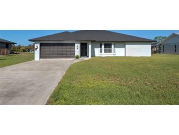 Newly built ranch home with a dark gray garage door and a spacious lawn at 7379 Snow Dr, Englewood, FL 34224