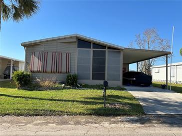 Tan single-wide manufactured home with carport and covered porch at 707 Riverview Cir, North Port, FL 34287