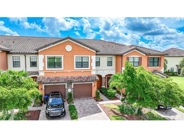 Two story townhome with orange exterior, two car garage, and landscaped front yard at 20149 Lagente Cir, Venice, FL 34293