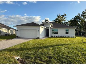 White house with a two-car garage and a well-manicured lawn at 25245 Delgado Dr, Punta Gorda, FL 33955