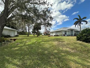 Single-story house with a large yard and mature trees at 2007 Omega Ct, North Port, FL 34288