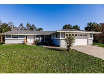 Ranch-style home with a two-car garage and lawn at 18370 Inwood Ave, Port Charlotte, FL 33948