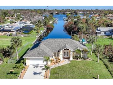 Single-Gathering home on canal with fenced yard, driveway, and lush landscaping at 18404 Lake Worth Blvd, Port Charlotte, FL 33948