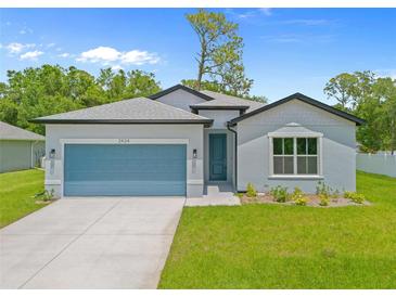 Charming single-story home featuring a light blue exterior, a well-kept lawn and a blue garage door at 2404 Hanford Ln, North Port, FL 34288