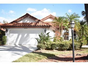 Charming home showcasing a red tile roof, two-car garage, and tropical landscaping at 956 Harbor Town Dr, Venice, FL 34292