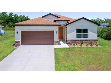 Charming single-story home with a two-car garage and a well-manicured lawn at 1415 Nackman Rd, North Port, FL 34288