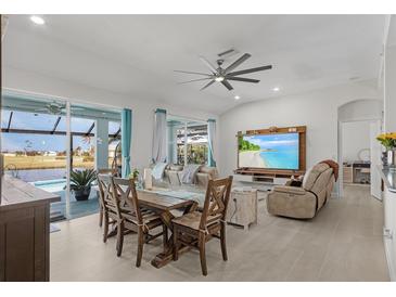 Bright living room featuring a dining table, ceiling fan, and a large sliding glass door that opens to the pool at 24004 Vincent Ave, Punta Gorda, FL 33955