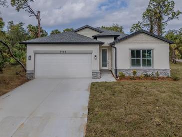 One-story house with white siding, gray stone accents, and a two-car garage at 3705 Baynes Rd, North Port, FL 34288