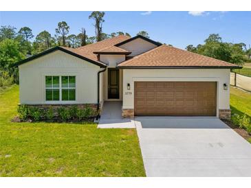Charming single-Gathering home featuring a manicured lawn, a two-car garage, and a welcoming entrance with stone accents at 3779 Clearfield St, North Port, FL 34286