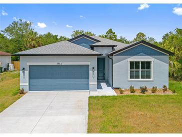 Charming single-story home featuring a two-car garage, manicured lawn, and modern architectural details at 3883 Dominic St, North Port, FL 34288