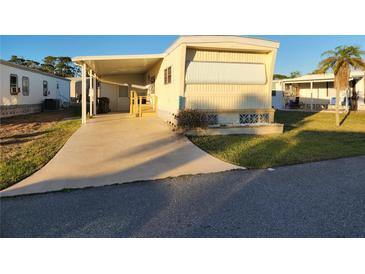 Charming mobile home features a covered parking area and well-maintained lawn with landscaped details at 5524 Holiday Park Blvd, North Port, FL 34287