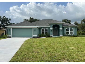 Charming single-story home with a well-manicured lawn, attached two-car garage, and light blue exterior at 27462 Pasto Dr, Punta Gorda, FL 33983
