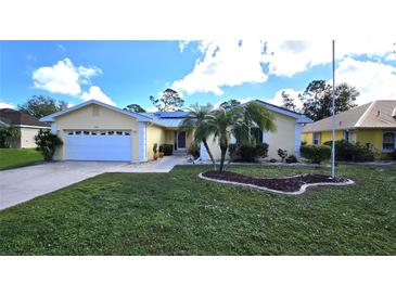 Single-story house with a white garage door and landscaped yard at 416 Torrington St, Port Charlotte, FL 33954