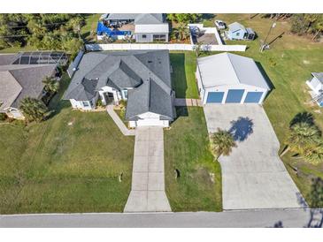 Aerial view of a home with a large garage, concrete driveway, and well-maintained lawn at 17152 Wintergarden Ave, Port Charlotte, FL 33948