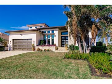 Modern single-Gathering home with light-colored walls, dark-brown garage door, and landscaped front yard at 681 Macedonia Dr, Punta Gorda, FL 33950