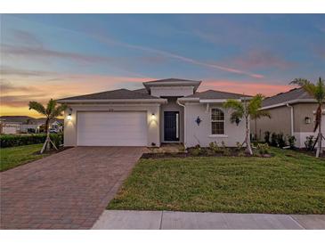 Two-story house with gray exterior, brick driveway, and landscaped lawn at 16138 Highgate St, Port Charlotte, FL 33953