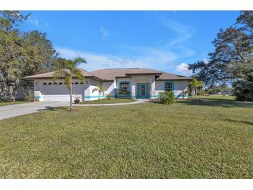 Charming single-story home with well-manicured lawn, blue trim, and a two-car garage at 182 Santarem Cir, Punta Gorda, FL 33983