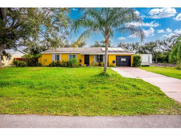 Bright yellow house with a large green lawn, palm tree, and driveway at 1238 Ramsdel St, Port Charlotte, FL 33952