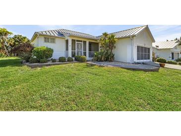 Single-story house with metal roof, landscaped lawn, and screened porch at 17458 Fuego Ln, Punta Gorda, FL 33955