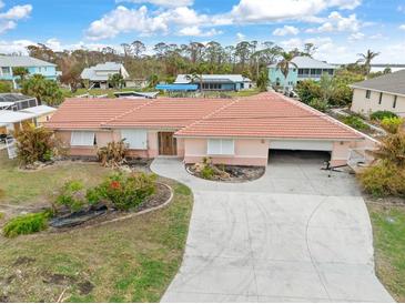 An exterior elevation view of a single-story home featuring a tile roof, driveway and attached garage at 1923 Pennsylvania Ave, Englewood, FL 34224