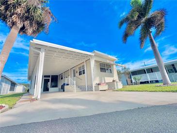Charming single-story home with a carport and manicured lawn and a front yard with palm trees in Harbor Cove at 207 Blackburn Blvd, North Port, FL 34287
