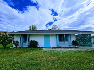 Charming single-story home with a teal door and well-manicured lawn at 683 W Tarpon Nw Blvd, Port Charlotte, FL 33952