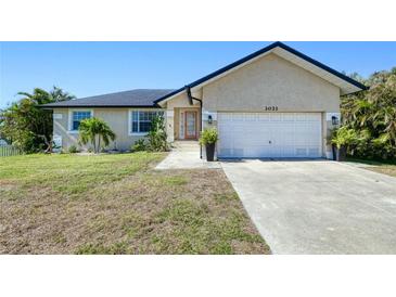 Tan house with a dark roof, white garage door, and landscaping at 3021 Palm Dr, Punta Gorda, FL 33950