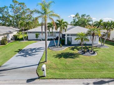 Single-story home with metal roof, palm trees, and landscaped yard at 3014 Guadalupe Dr, Punta Gorda, FL 33950