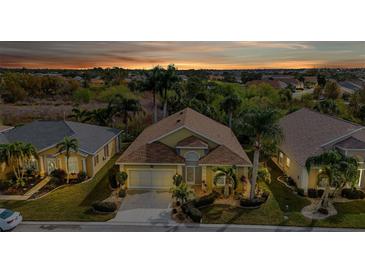 Aerial view of a charming house with a two-car garage and lush landscaping at 1636 Palace Ct, Port Charlotte, FL 33980