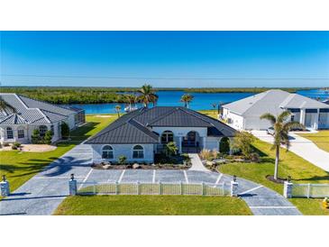 Stunning waterfront home with lush landscaping, a pristine white fence, and a gorgeous dark roof at 5117 Collingswood Blvd, Port Charlotte, FL 33948