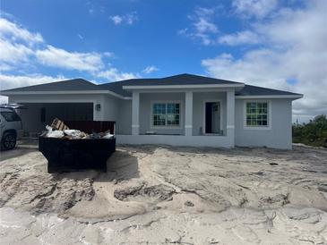 New construction home with a light gray exterior, dark roof, and an attached two-car garage at 13541 Jeronimo Ln, Port Charlotte, FL 33981