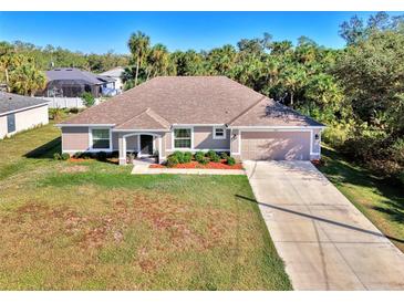 Single-story home with a large yard, driveway, and attached garage at 1858 Capitol St, North Port, FL 34288