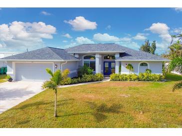 Charming single-story home with blue double doors, gray roof, and landscaped yard at 430 Spring Lake Nw Blvd, Port Charlotte, FL 33952