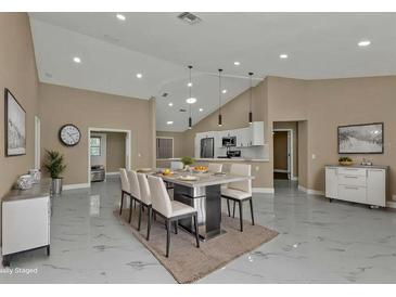 Open-concept dining area with modern lighting, sleek marble floors, and a view to the kitchen at 2387 Tamarind St, Port Charlotte, FL 33948