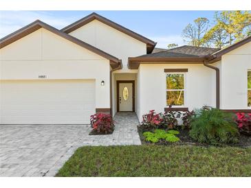White house with brown roof, paver driveway, and landscaping at 14059 Gailwood Ave, Port Charlotte, FL 33953