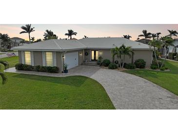 One-story home with a gray brick facade, landscaped lawn, and a paver driveway at 2701 Bay Ct, Punta Gorda, FL 33950