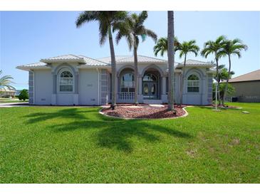 Charming single-story home with a landscaped front yard and beautiful curb appeal and mature palm trees at 649 Maltese Dr, Punta Gorda, FL 33950