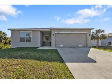 Charming single-story home featuring a well-maintained lawn, a gray color scheme, and a two-car garage at 18043 Avonsdale Cir, Port Charlotte, FL 33948