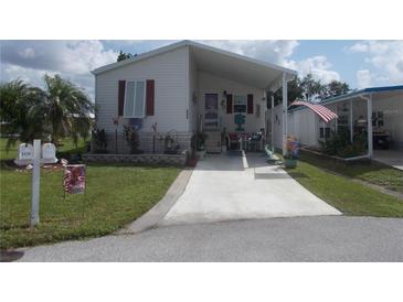Mobile home with carport, landscaped yard, and paved driveway at 6546 Greenview Ct, North Port, FL 34287