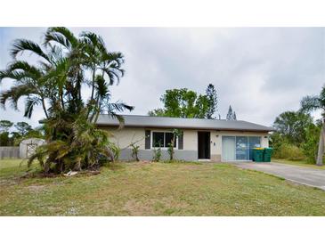 Front exterior of a single-story home with a driveway, some landscaping and palm trees at 11332 8Th Ave, Punta Gorda, FL 33955