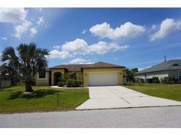 Charming one-story home with yellow siding, a two-car garage, and a well-manicured front lawn at 25115 Esmeralda Ct, Punta Gorda, FL 33955