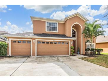 Two-story house with tan exterior, three-car garage, and landscaped yard at 10721 Banfield Dr, Riverview, FL 33579