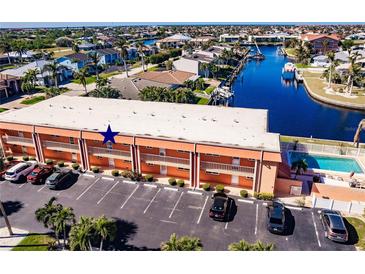 Aerial view of condo building, pool, parking, and canal at 1345 Mediterranean Dr # A203, Punta Gorda, FL 33950